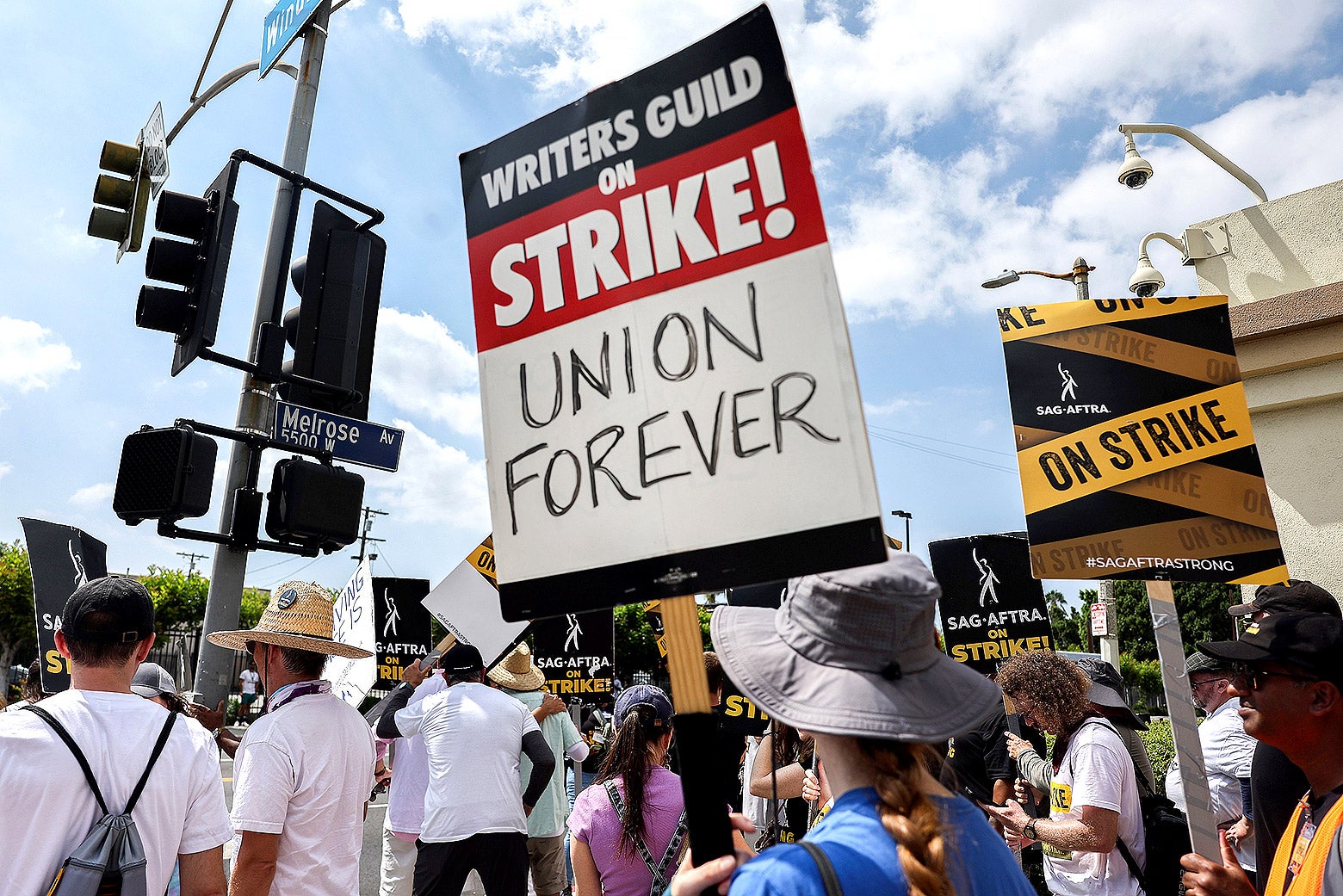 People hold signs that say things like "Writers Guild on Strike. Union forever."